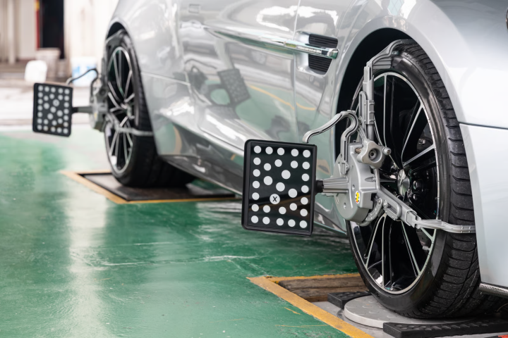 High precision optical wheel alignment target clamps attached to the wheels of a silver sports car during suspension tuning